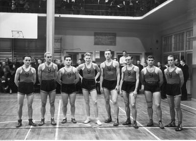 Boom na amerykańską koszykówkę zaczął się w l. 20 wśród młodzieży szkolnej i akademickiej. Podobnie jak w przypadku siatkówki także koszykówka przechodziła okres swobody przepisów i reguł rywalizacji. Unifikacja pojawiła się po utworzeniu w 1928 r. wspomnianego wyżej Polskiego Związku Gier Sportowych. Wkrótce rozegrano pierwsze mistrzostwa Polski mężczyzn, a w roku 1929 r. kobiet. Na fotografii drużyna koszykarzy YMCA (Związek Chrześcijańskiej Młodzieży Męskiej) na sali gimnastycznej przed meczem ze studentami amerykańskimi z Berlina w Warszawie w 1935 r. Zbiory NAC